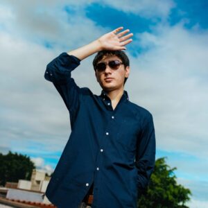Young man shielding eyes from sun on rooftop