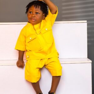 A cute boy poses, wearing a yellow outfit.