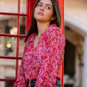 a woman standing next to a red phone booth