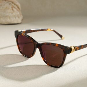 Tortoiseshell sunglasses with gold accents on a light surface.