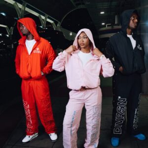 Three people in matching tracksuits outdoors at night.